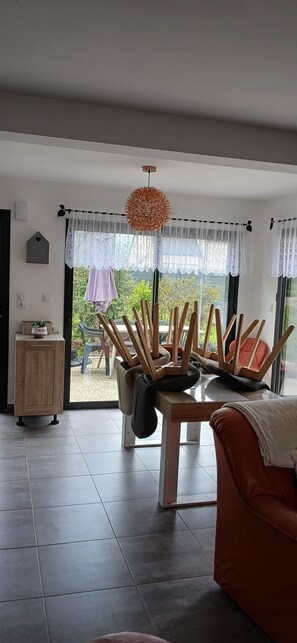 A modern living room with a dining area, large windows, and a view of the outdoors. - Single-family home in a very quiet neighborhood, 2 km³ from the beach. (Concarneau)