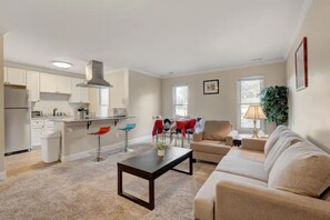 Ein modernes Wohnzimmer mit Sofa, Couchtisch und Essbereich mit Stühlen und Tisch.