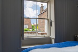 Ein Schlafzimmer mit Fenster, Bett und Heizkörper.