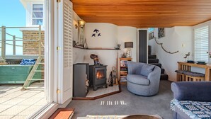 A cozy living room with a fireplace, a blue armchair, and a wooden ceiling. - Pip's Lookout, St Margaret's Bay (St Margaret's Bay)