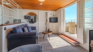 A living room with a sofa, a coffee table, a TV, and a view through a door. - Pip's Lookout, St Margaret's Bay (St Margaret's Bay)