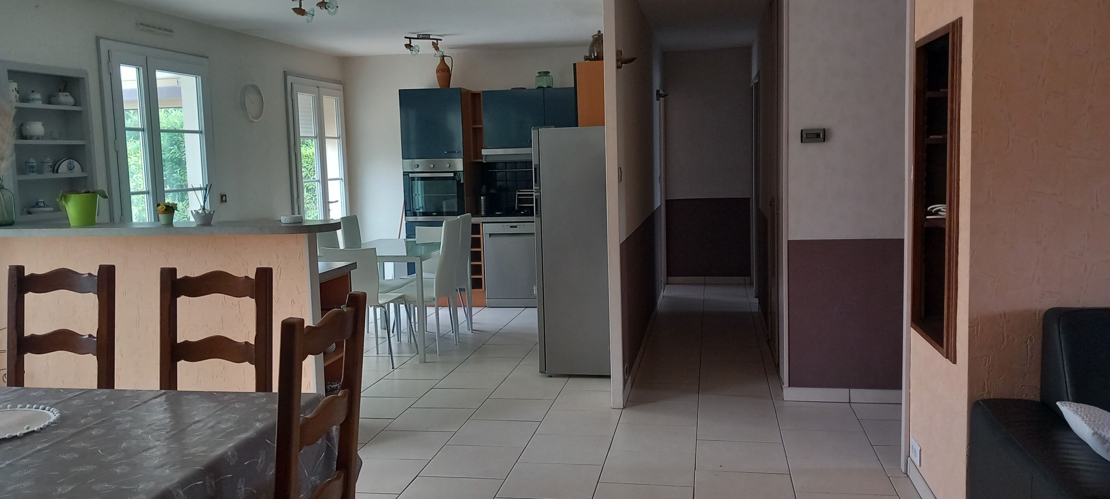 A kitchen with white cabinets, a dining table with chairs, and a refrigerator.