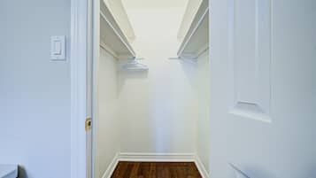 Ein schmaler Korridor mit weißen Wänden und Holzboden, der zu einem Schrank mit einer Tür am Ende führt.