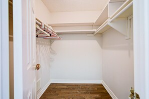 A narrow hallway with a wooden floor, white walls, and a door with a brass handle.