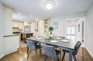 A spacious kitchen with a large island, wooden cabinets, and a dining area with a glass table and chairs. - Entire Stylish Classic(Upper)House in RH (Richmond Hill)