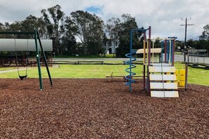 A playground with a swing set and a climbing structure.