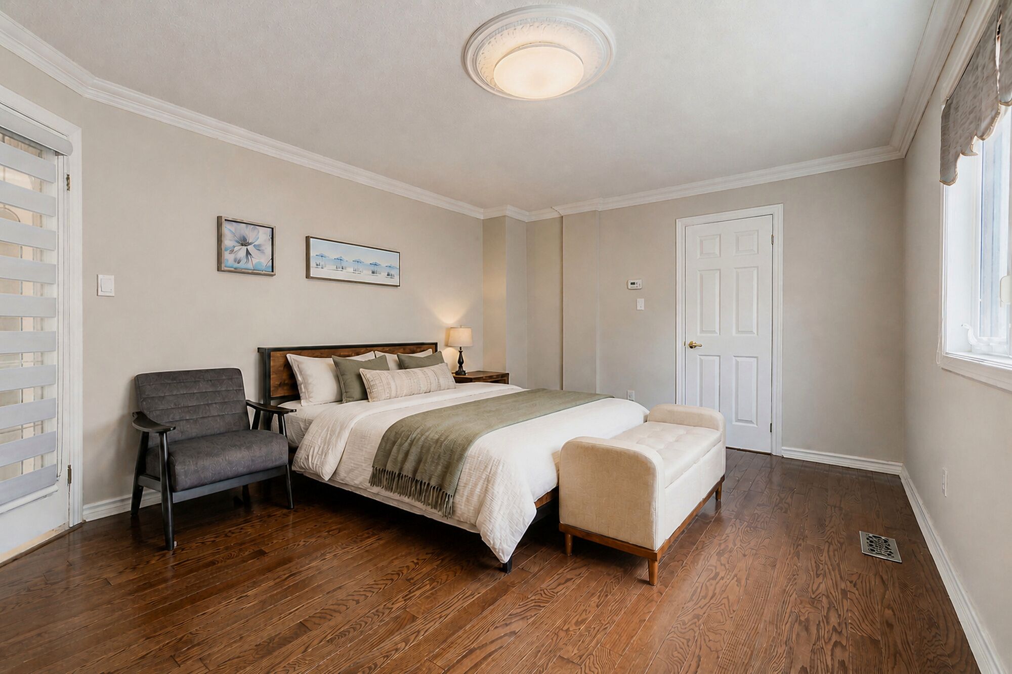A bedroom with a bed, two chairs, a nightstand, and a door.