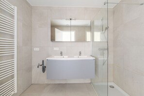A modern bathroom with a glass shower enclosure, a double sink vanity, and a large mirror. - 2 bedroom accommodation in Wenduine (Wenduine)