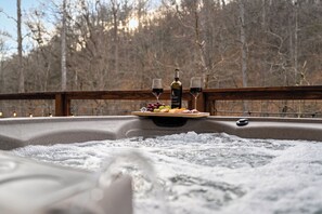 Ein Whirlpool mit Holzterrasse, umgeben von einem Wald.
