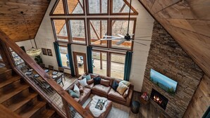Amplio espacio tipo loft con un ventanal grande, una chimenea y una escalera.