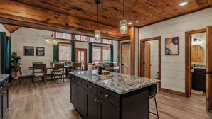 Una cocina amplia con una isla grande, techo de madera y un comedor con mesa y sillas.