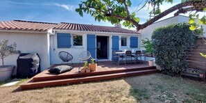 Un patio con mobili da esterno, una griglia coperta e un piccolo giardino.