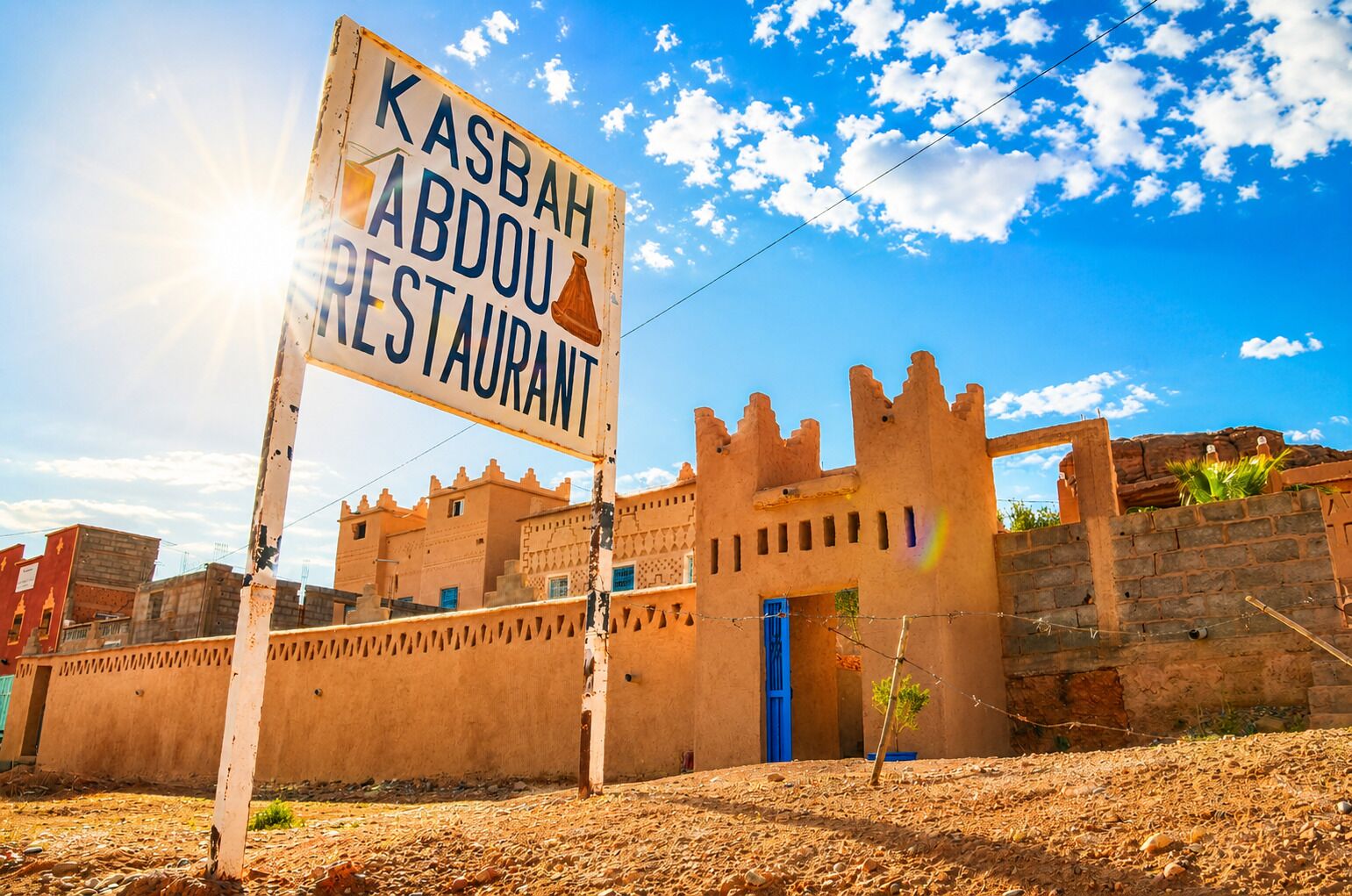 A sign for Kasbah Abdou Restaurant in front of a castle-like building.