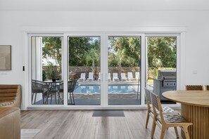 A spacious indoor area with a pool, outdoor seating, and a grill. - Black Pearl | Steps to Beach | Heated Pool & Spa | Free Golf Cart | Game Rooms (Destin)