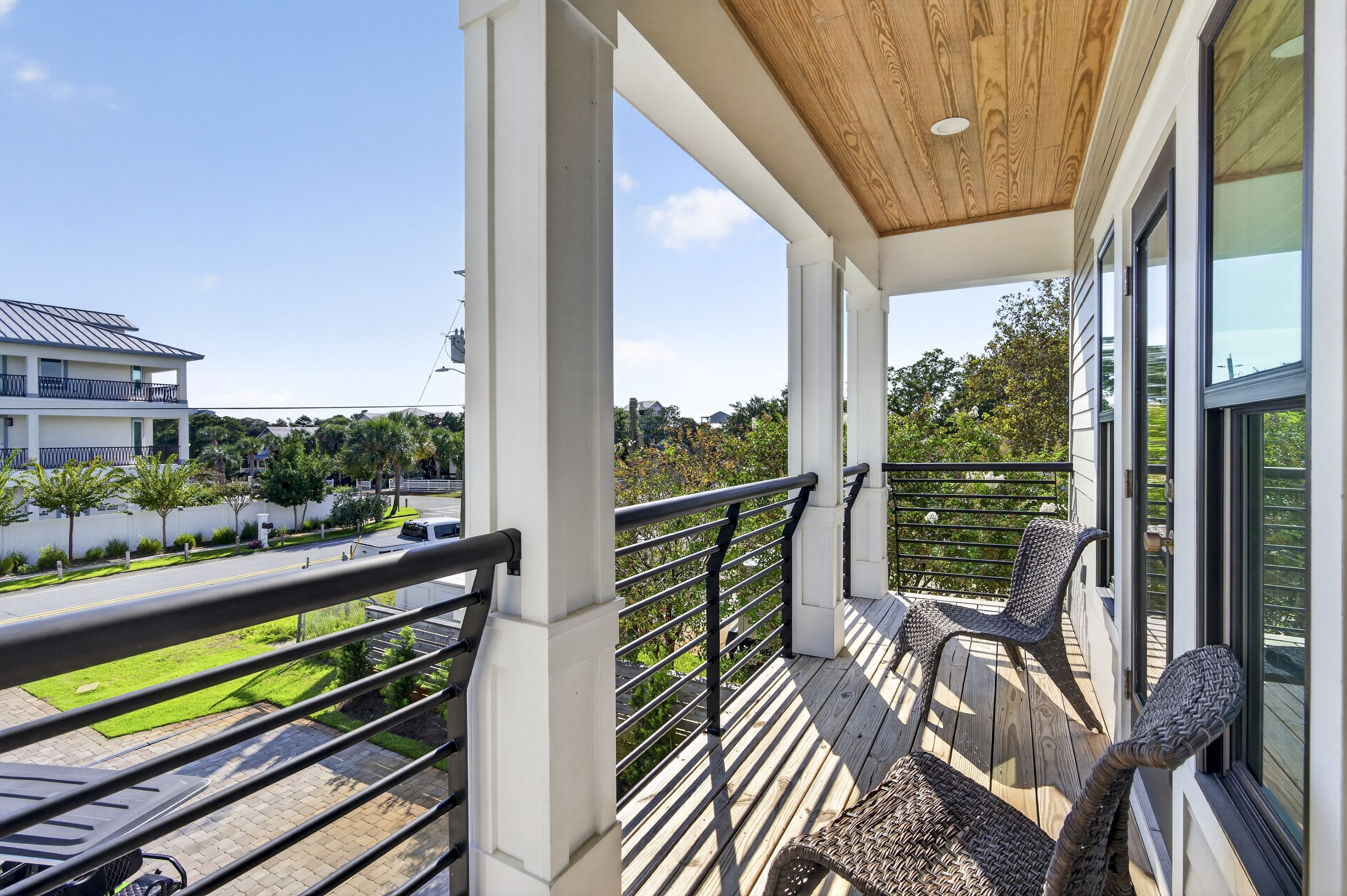 Varanda com vista para uma área residencial, teto de madeira e uma cadeira de vime.