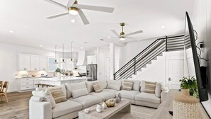 A modern living room with a sectional sofa, a coffee table, and a TV on a wooden stand. - Black Pearl | Steps to Beach | Heated Pool & Spa | Free Golf Cart | Game Rooms (Destin)