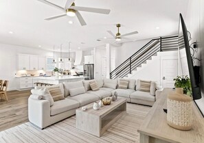 Ein modernes Wohnzimmer mit einem Ecksofa, einem Couchtisch und einem Fernseher auf einem Holzgestell.