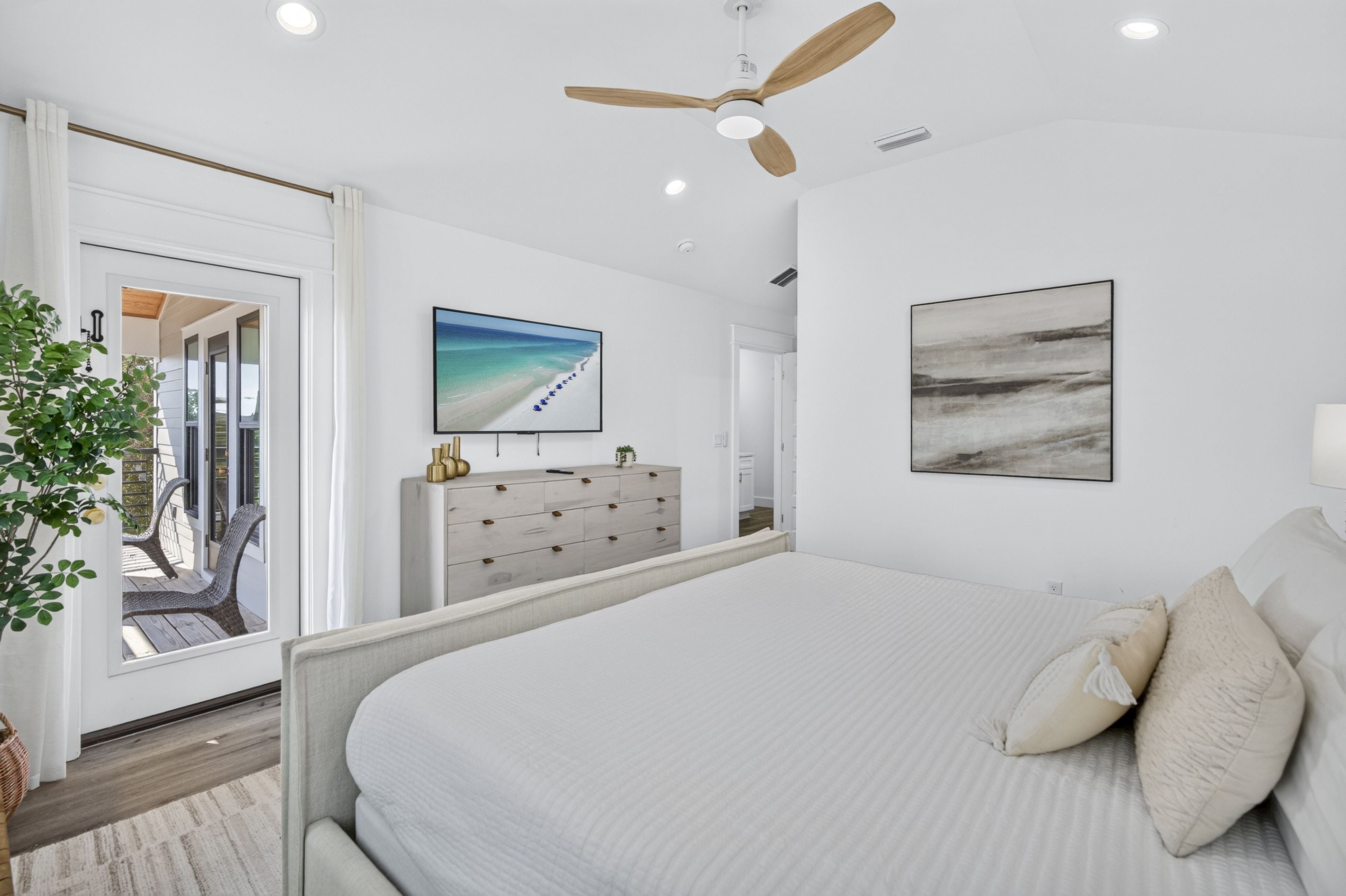 Quarto com cama, penteadeira, televisão e ventoinha no teto.