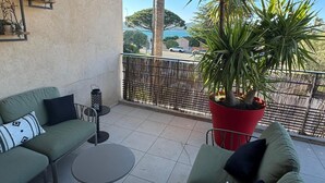 A balcony with a green sofa, a round table, a potted plant, and a view of a street and mountains. - Roméo Loft Prestige House with Ocean Views on the Outskirts of Saint-Tropez (Gassin)