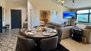 A modern living room with a dining area, a sofa, a TV, and a view of the outdoors. - Roméo Loft Prestige House with Ocean Views on the Outskirts of Saint-Tropez (Gassin)