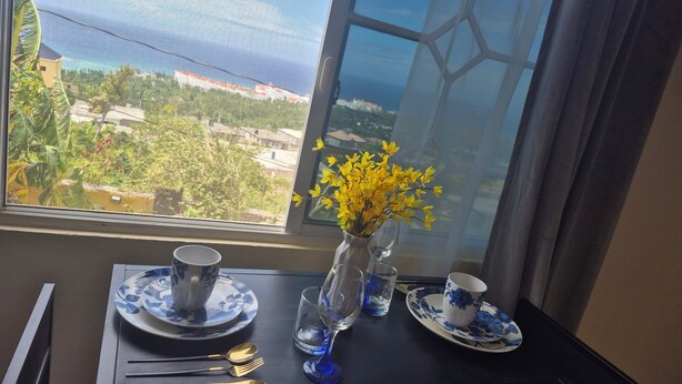 Et spisebord med en vase med gule blomster, blå og hvide tallerkener samt bestik.