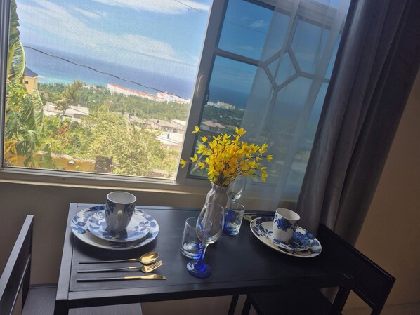 A dining table with a vase of yellow flowers, blue and white plates, and cutlery.