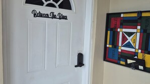 A white door with a window and a sign that reads 'Between the Blues.'