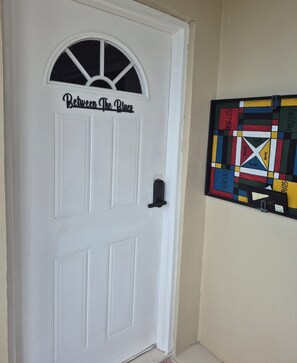 A white door with a window and a sign that reads 'Between the Blues.' - Cozy Studio Guests Suite in Runaway Bay (Runaway Bay)