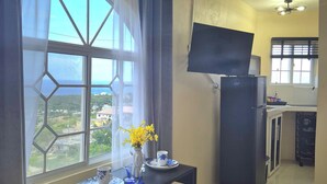A room with a dining table, a TV, and a refrigerator.