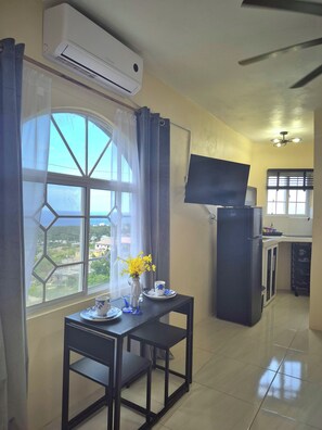A room with a dining table, a TV, and a refrigerator. - Cozy Studio Guests Suite in Runaway Bay (Runaway Bay)
