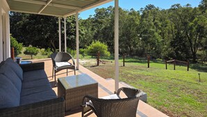 A covered outdoor seating area with wicker furniture and a glass-top table.