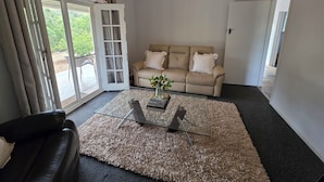 A living room with a sofa, a coffee table, and a glass door leading outside.