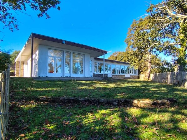 Une maison de plain-pied dotée d’une grande véranda à l’avant, de fondations en pierre et d’une pelouse bien entretenue.