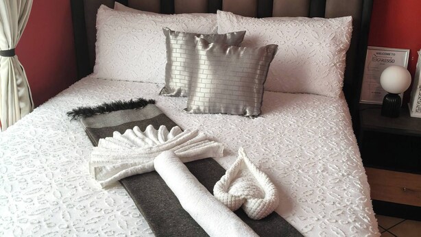 Un lit bien fait, avec une couvre-lit à motifs, des oreillers et des serviettes soigneusement disposés sur le lit.