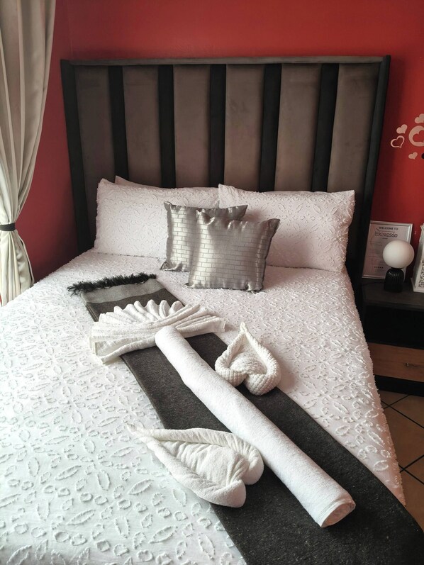 A neatly made bed with a patterned bedspread, pillows, and towels arranged on the bed.