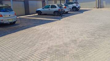 A parking area with cars, a paved surface, and a building with a flat roof in the background.