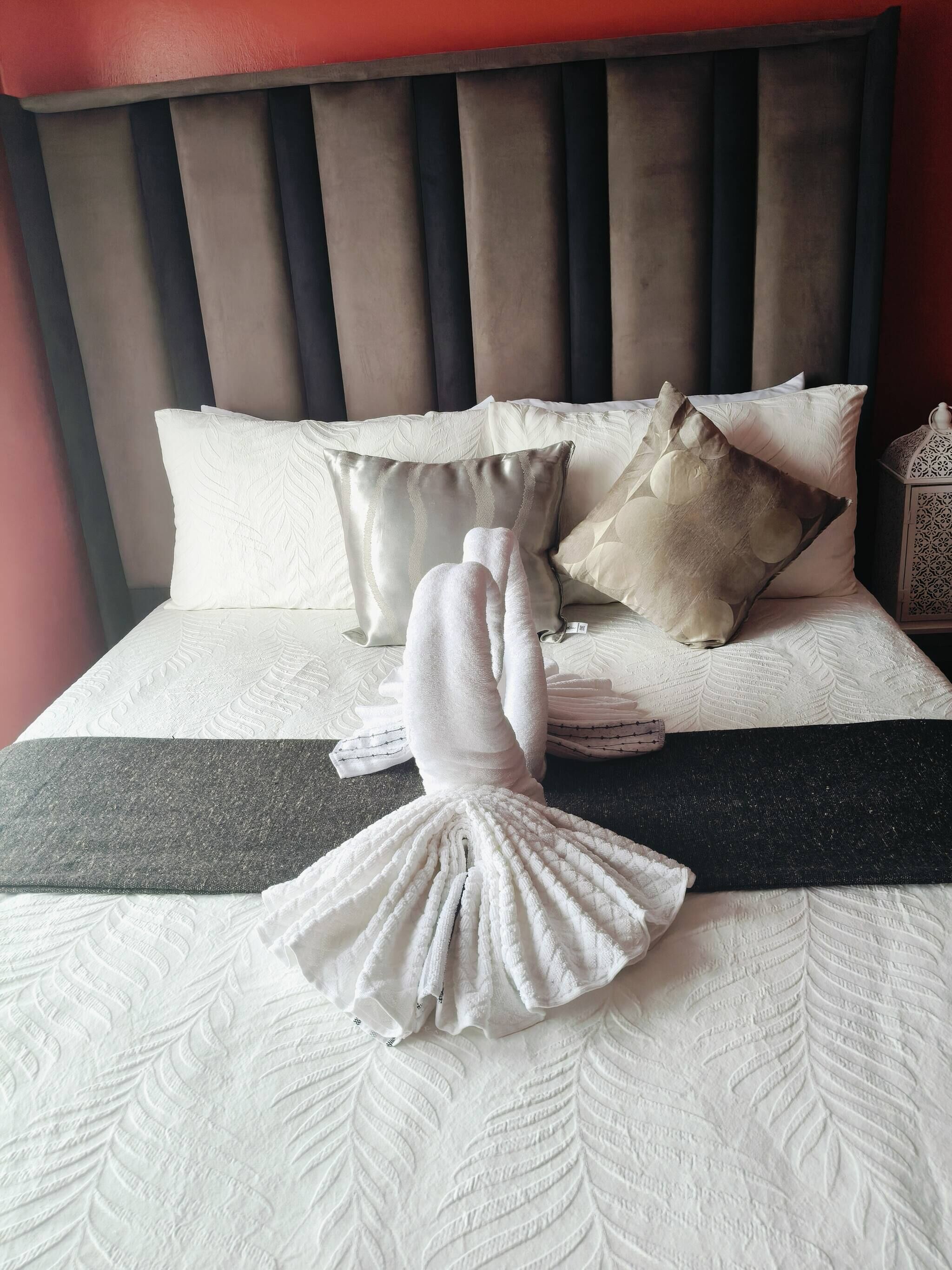 A neatly made bed with a white duvet, a decorative pillow, and a folded towel.