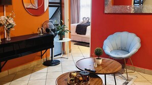 Un salon moderne comprenant un canapé, une table basse, un fauteuil bleu, un téléviseur et un coin repas avec une table et des chaises.