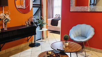 Una sala moderna con un sofá, una mesa de centro, un sillón azul, un televisor y un comedor con una mesa y sillas.