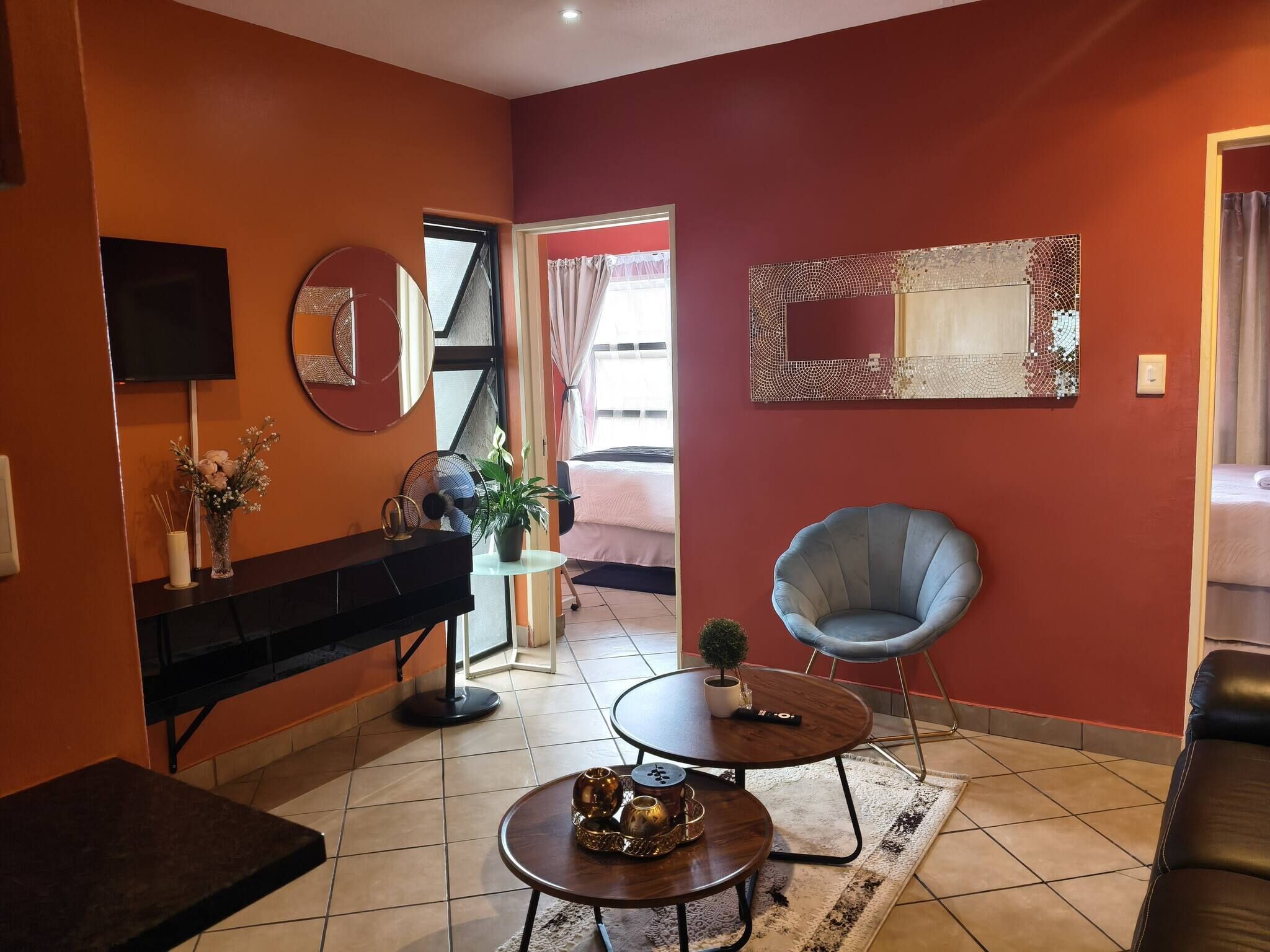 Una sala de estar con un piano, una mesa redonda, un sillón azul y un espejo en la pared.