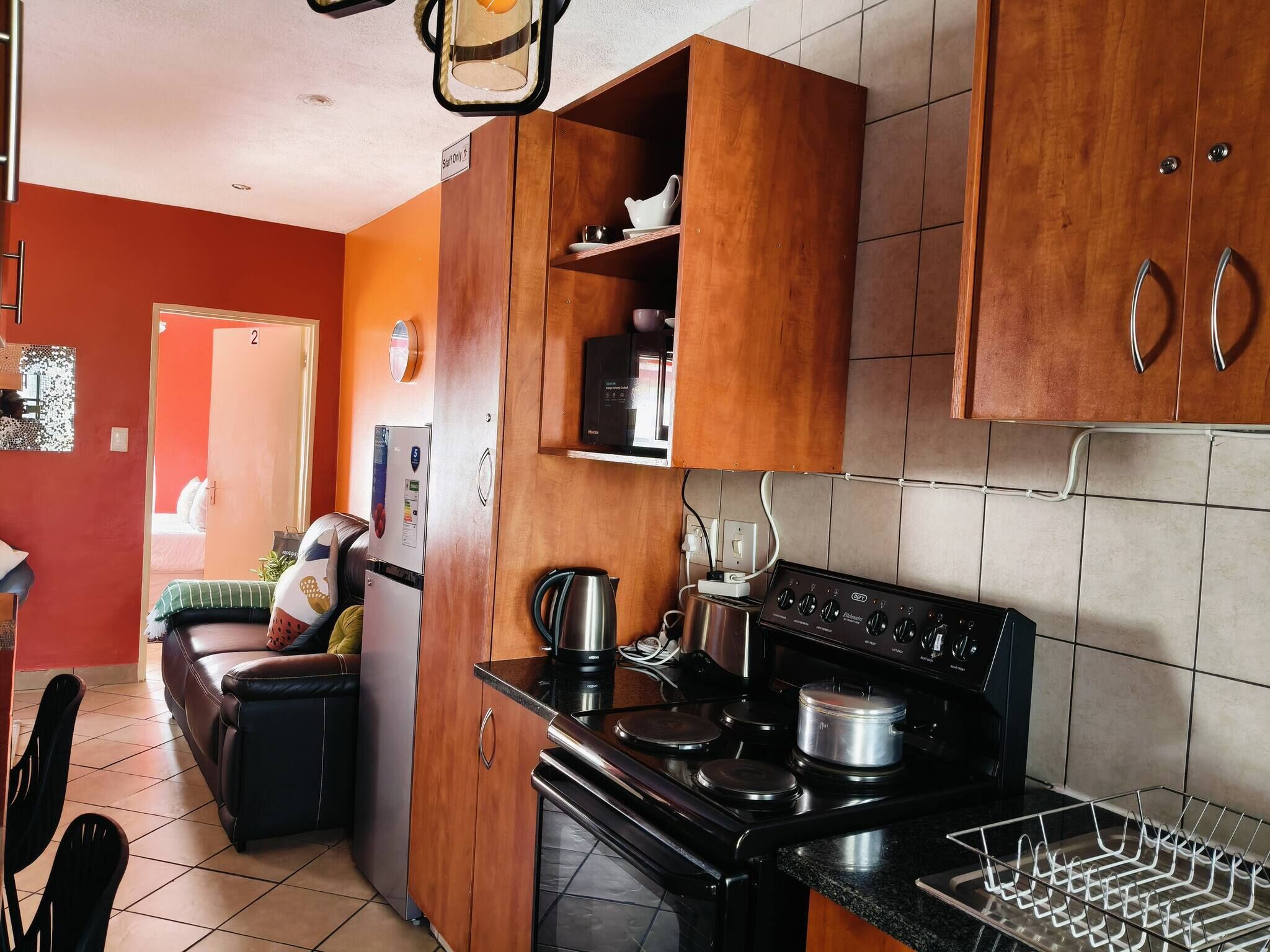 Une cuisine avec des meubles de rangement en bois, une cuisinière, une bouilloire et un réfrigérateur.