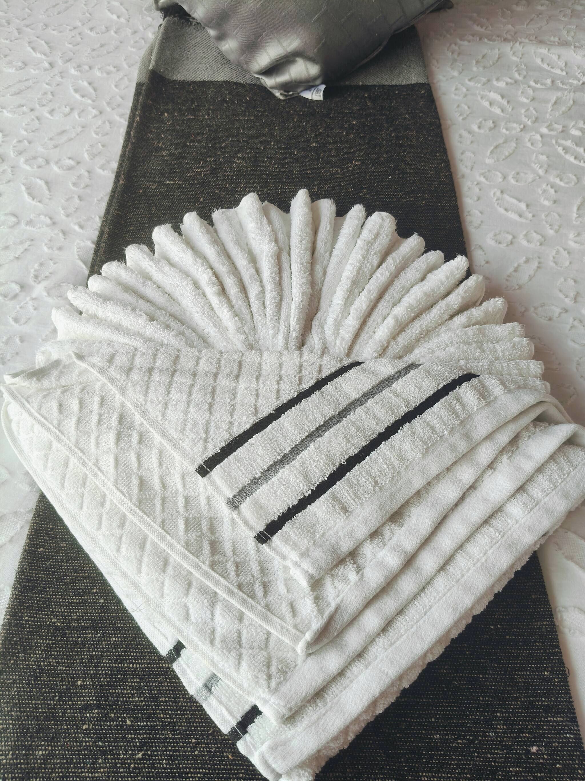 A stack of white towels with black stripes on a dark-colored surface.