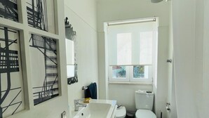 A compact bathroom with a white sink, toilet, and a window above the toilet. - Bright and spacious, just 20 meters from the subway station in a family-friendly neighborhood. (Lisboa)