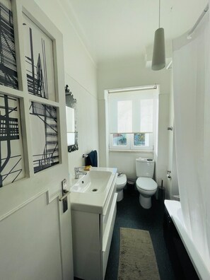 Ein kleines Badezimmer mit einem weißen Waschbecken, einer Toilette und einem Fenster über der Toilette.
