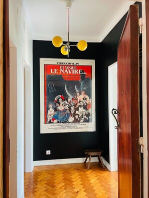 Ein Flur mit schwarzem Wandbelag, Holzboden und einem 'Et Vogue Le Navire'-Poster an der Wand.