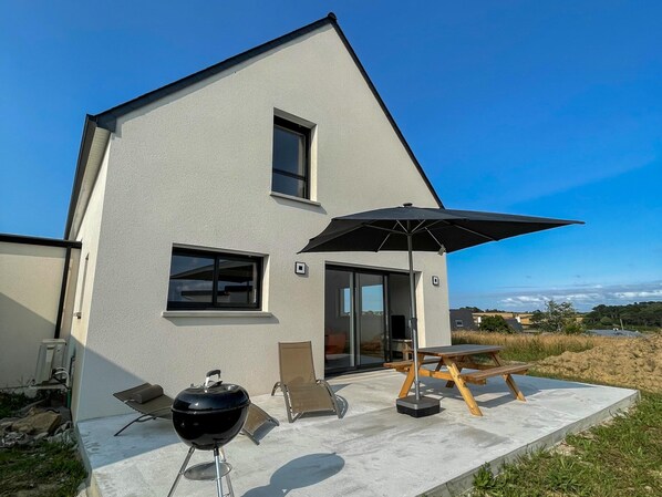 A modern house with a patio, a barbecue grill, a table, and a chair. - House in Saint-pabu Near Beach (Saint-Pabu)