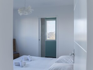 A minimalist bedroom with a bed, a door, and a view of the outdoors. - House in Saint-pabu Near Stunning Beaches (Saint-Pabu)
