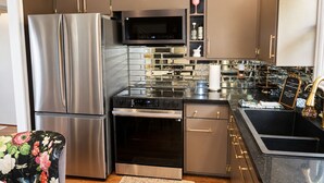 A modern kitchen with stainless steel appliances, a microwave, and a built-in oven. - The Long Weekend Cottage Charming English Cottage Minutes from Main Street (Fredericksburg)