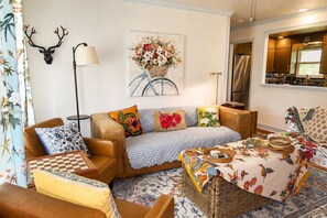 Ein gemütliches Wohnzimmer mit einer Couch, Sesseln, einem Couchtisch und einem an der Wand befestigten Hirschkopf.