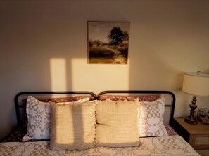 Un dormitori amb llit, almoines, una petita taula de nit, una làmpada i un quadre a la paret.